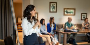 Elena sitzt am Tisch mit ihrem Laptop und hat dabei einen Ausblick auf die Berge | Ski-Office | Kraus & Partner - Transformation Experts